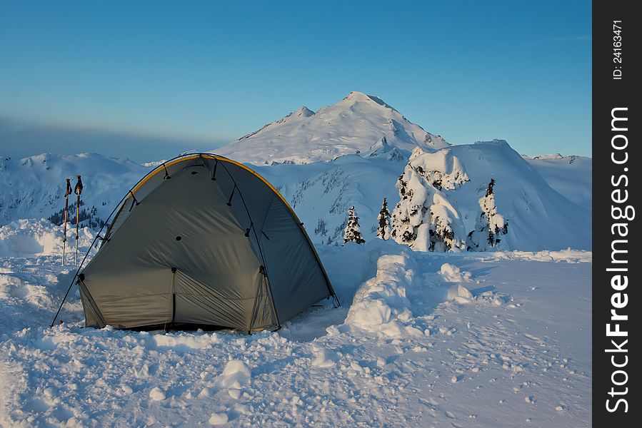 A tent is pitched in snow with Mt. Baker in Washington State in background. A tent is pitched in snow with Mt. Baker in Washington State in background