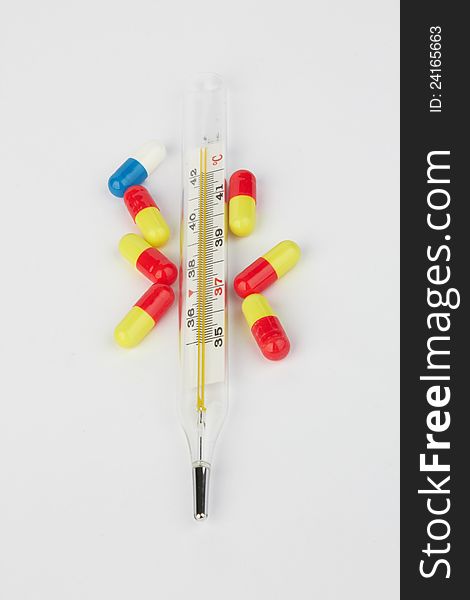 Thermometer and pills on white