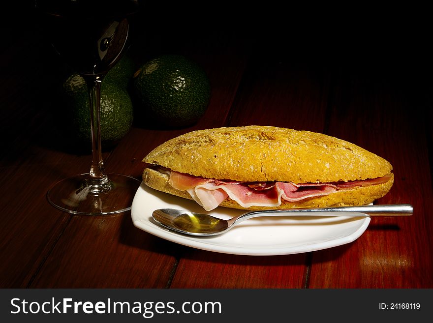 Jamon - Spanish Cured Ham on Brown Bread with spoon of olive oil on a wooden table
