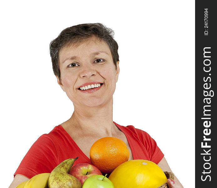 A happy smiling middle-aged woman holding a basket full of fruits. Isolated over white.