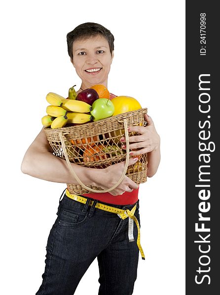 A happy smiling middle-aged woman holding a basket full of fruits. Isolated over white.