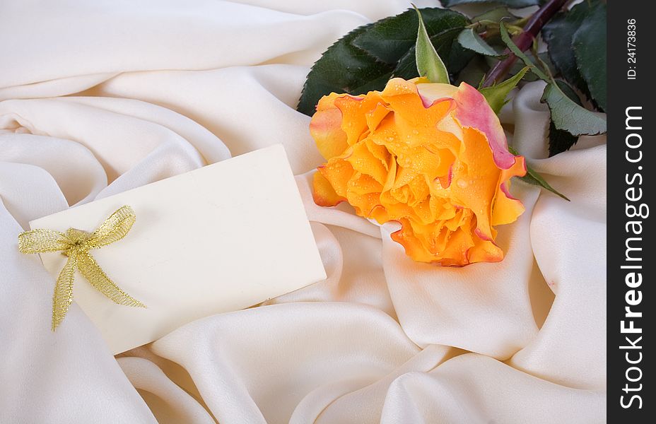 Yellow rose and a card on a gentle silk