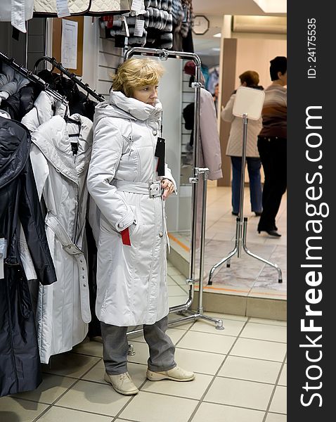 Woman tries on coat in shop of clothes