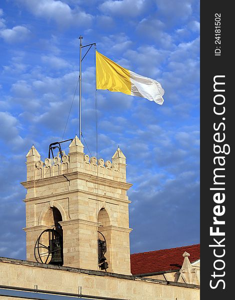 Bell tower with flag on the background of blue sky