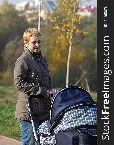 Mother with newborn in the pram walking in the park. Mother with newborn in the pram walking in the park