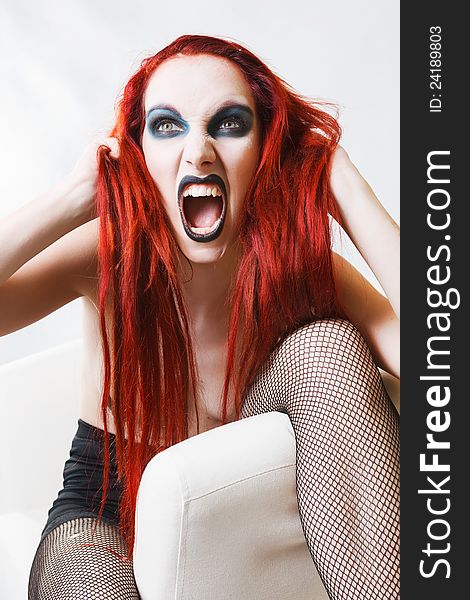 Studio shot of expressive gothic red haired woman with artistic makeup over white background. Studio shot of expressive gothic red haired woman with artistic makeup over white background