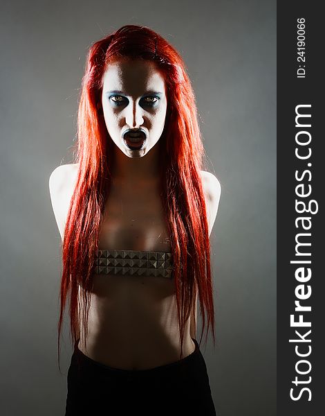 Studio shot of expressive gothic red haired woman with artistic makeup with dramatic light. Studio shot of expressive gothic red haired woman with artistic makeup with dramatic light