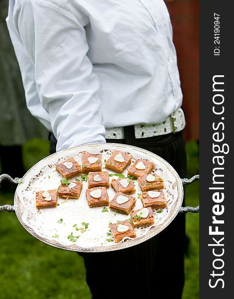 A waiter holding a platter with appetizers during a catered event. A waiter holding a platter with appetizers during a catered event