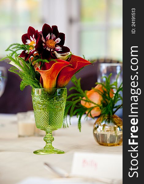 A small wedding centerpiece of flowers in a green vase