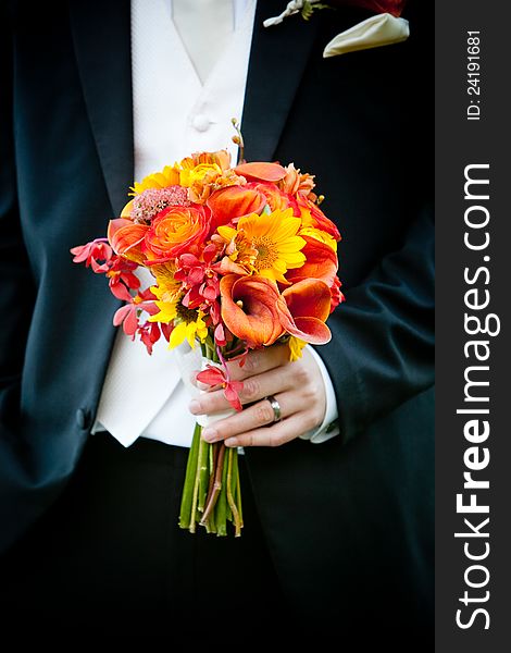 A bridal wedding bouquet of flowers being held by a groom