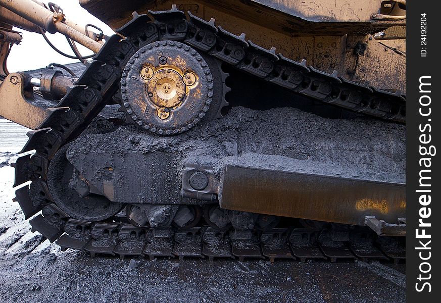 Bulldozer caterpillar tracks covered in coal dust