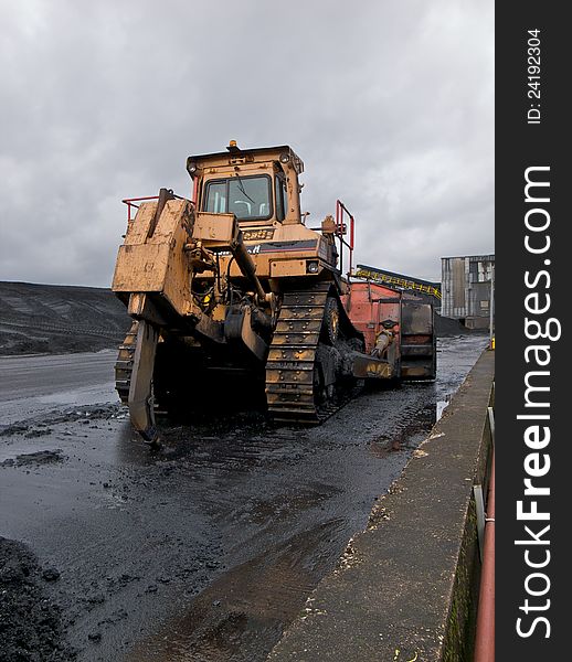 Bulldozer parked near a coal stock pile.