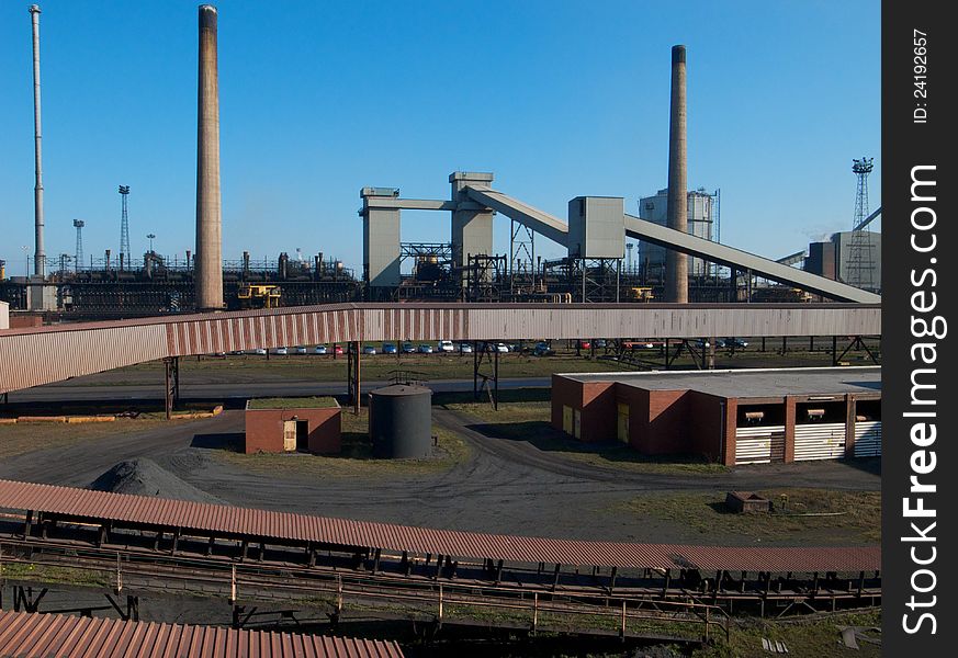 Industrial chimneys and conveyor belts in a coke manufacturing plant. Industrial chimneys and conveyor belts in a coke manufacturing plant.