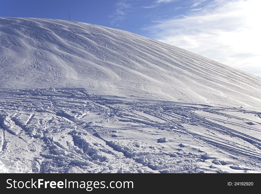 Alpine mountain covered with white snow with ski and snowboard tracks in sunset light. Alpine mountain covered with white snow with ski and snowboard tracks in sunset light