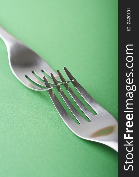 Two forks crossed on the green table