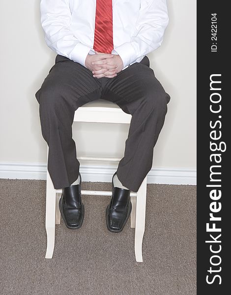 Businessman sitting in his high chair with his hands in his lap clasped and his feet on the chair. Businessman sitting in his high chair with his hands in his lap clasped and his feet on the chair
