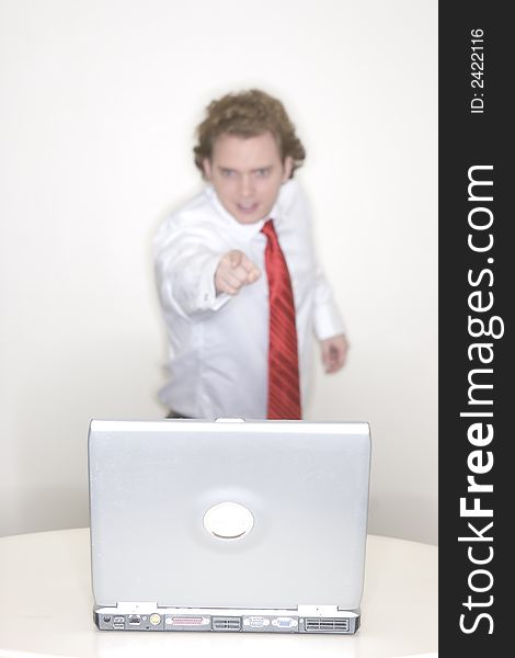 Businessman standing behind his laptop in his office with finger and arm pointing to his laptop. Businessman standing behind his laptop in his office with finger and arm pointing to his laptop