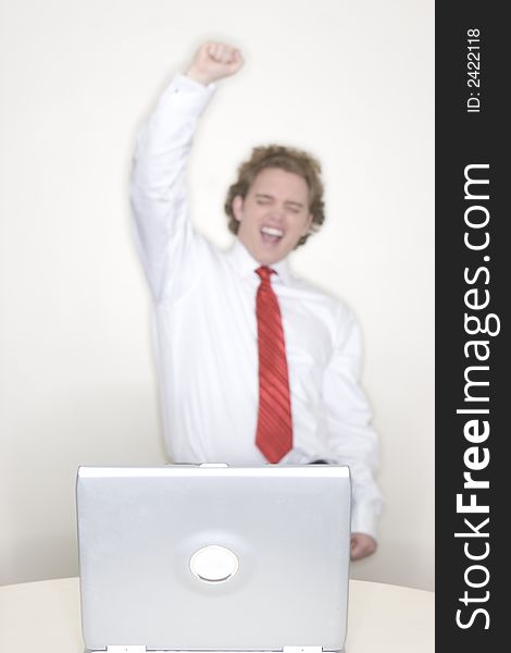 Businessman celebrating a victory while he stands behind his laptop in his office. Businessman celebrating a victory while he stands behind his laptop in his office