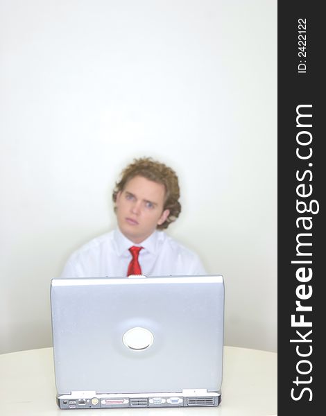 Businessman sitting behind his laptop with an inquisitive and puzzling look. Businessman sitting behind his laptop with an inquisitive and puzzling look