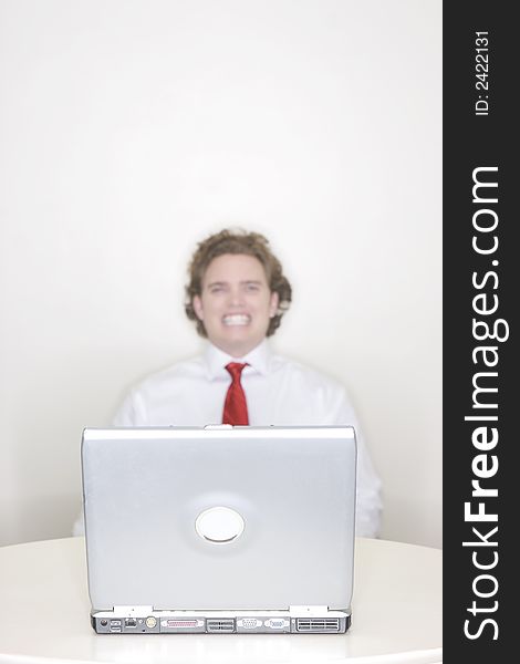 Businessman sitting behind his laptop with a large toothy smile. Businessman sitting behind his laptop with a large toothy smile