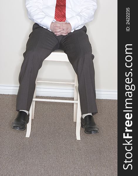 Businessman sitting on a high chair dangling his feet off the chair. Businessman sitting on a high chair dangling his feet off the chair