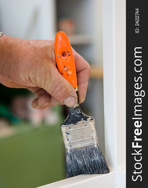 Craftsman restaurates a window with his paintbrush. Close-Up of Paintbrush and hand. Craftsman restaurates a window with his paintbrush. Close-Up of Paintbrush and hand.