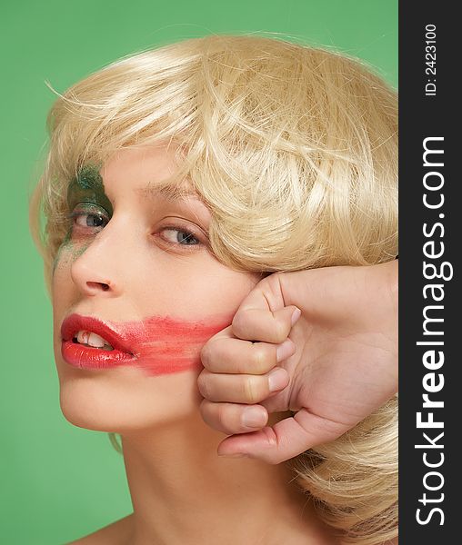 A beautiful girl in a wig. She smears lipstick on the face.