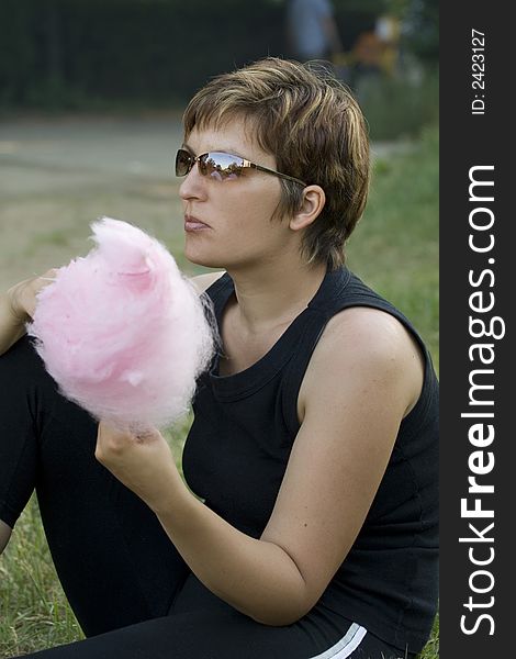 Women with sunglasses eating pink sweet candy outdoor