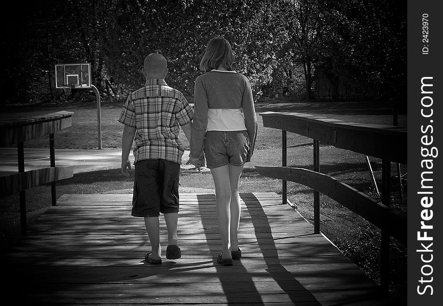 Brother & sister holding hands while crossing the bridge.

Black & White