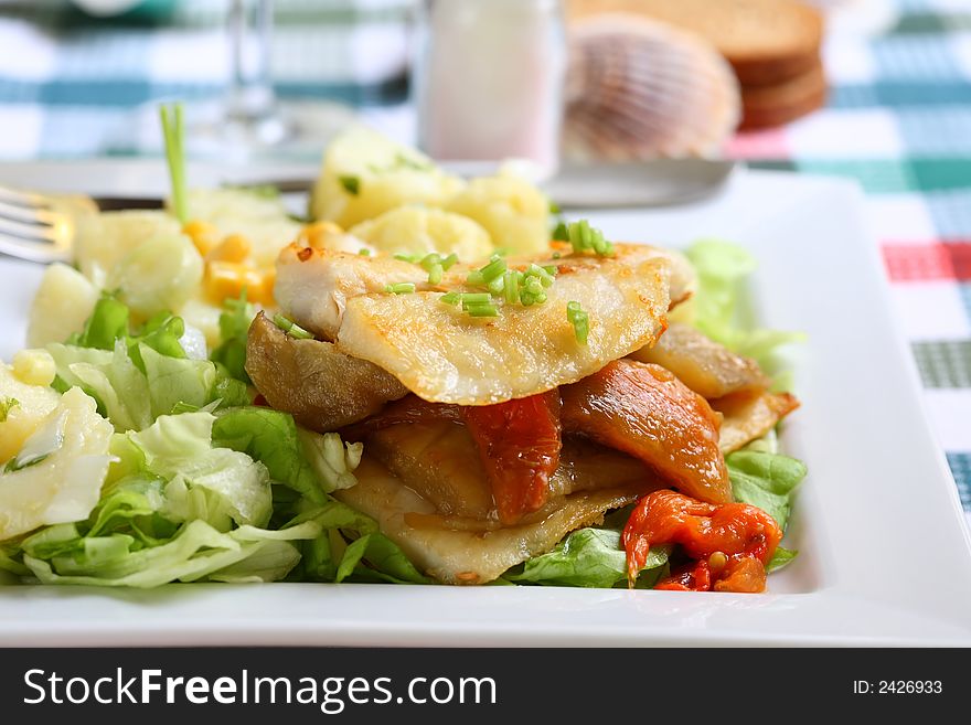 Grilled hake filet with roast pepper and aubergine on lettuce and potato salad. Grilled hake filet with roast pepper and aubergine on lettuce and potato salad