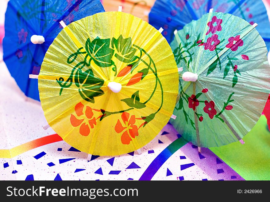 Colorful party drink umbrellas on a festive background paper. Colorful party drink umbrellas on a festive background paper.