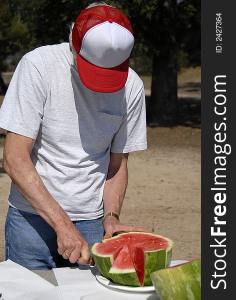 A men is cutting ripe watermelon