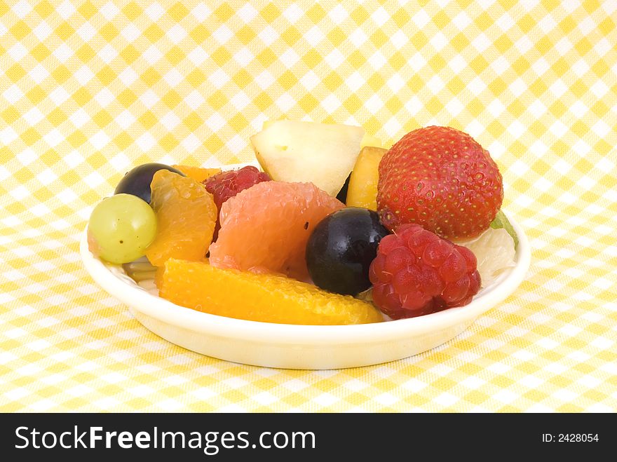 Fruit-salad on a plate with yellow-white background