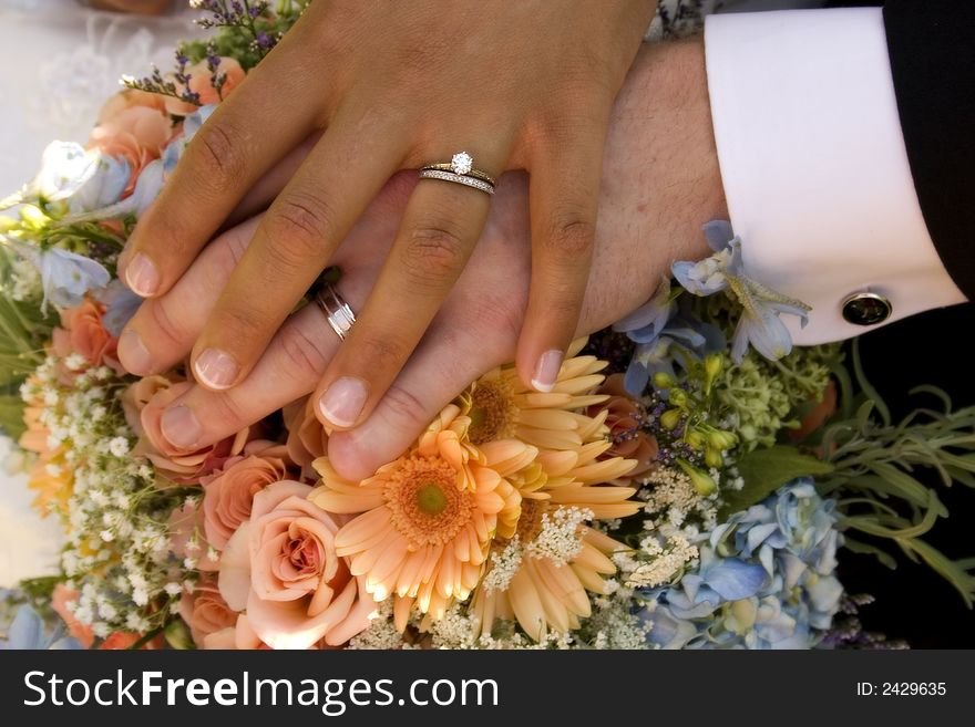Bride and groom's hands over wedding bouquet. Bride and groom's hands over wedding bouquet