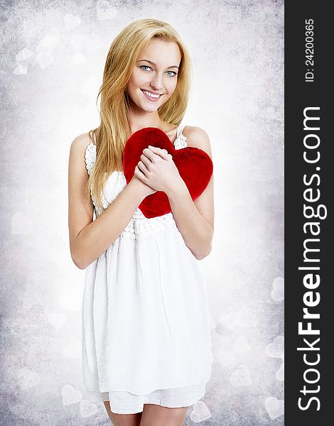 Sweet smiling young blond woman holding red heart shape pillow. Sweet smiling young blond woman holding red heart shape pillow