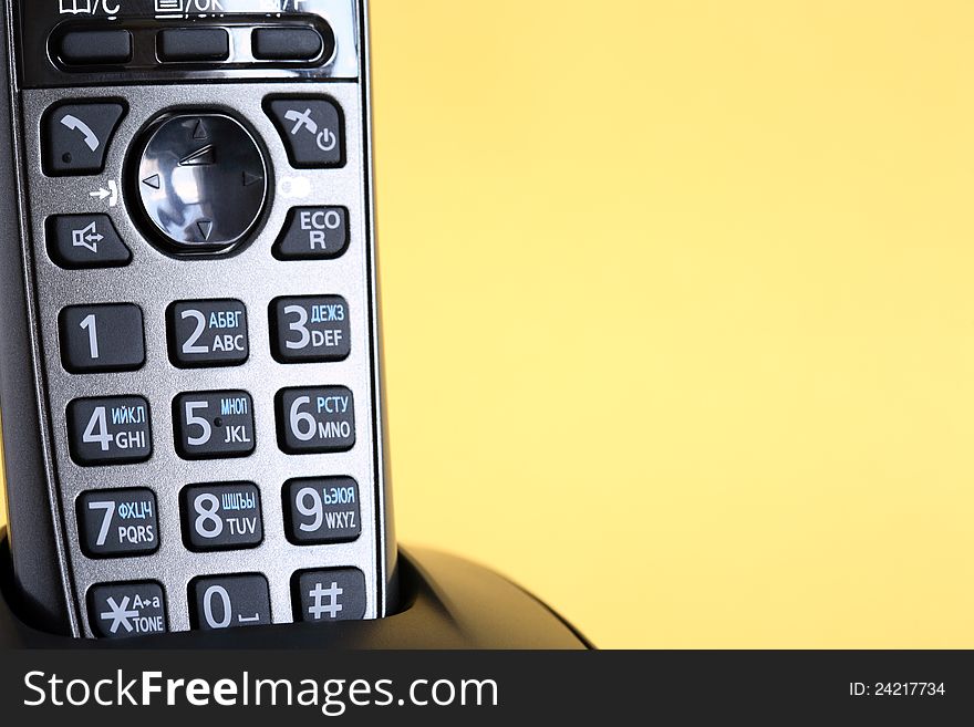 Modern black wireless telephone on yellow background with free space for text