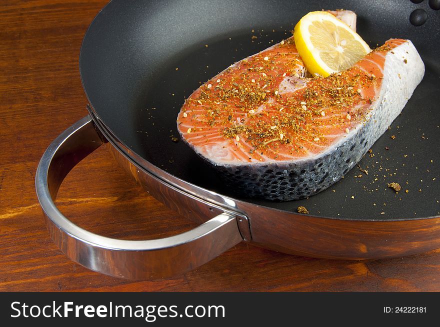 Fresh Pacific Salmon steak with herbs and spices on a frying pan