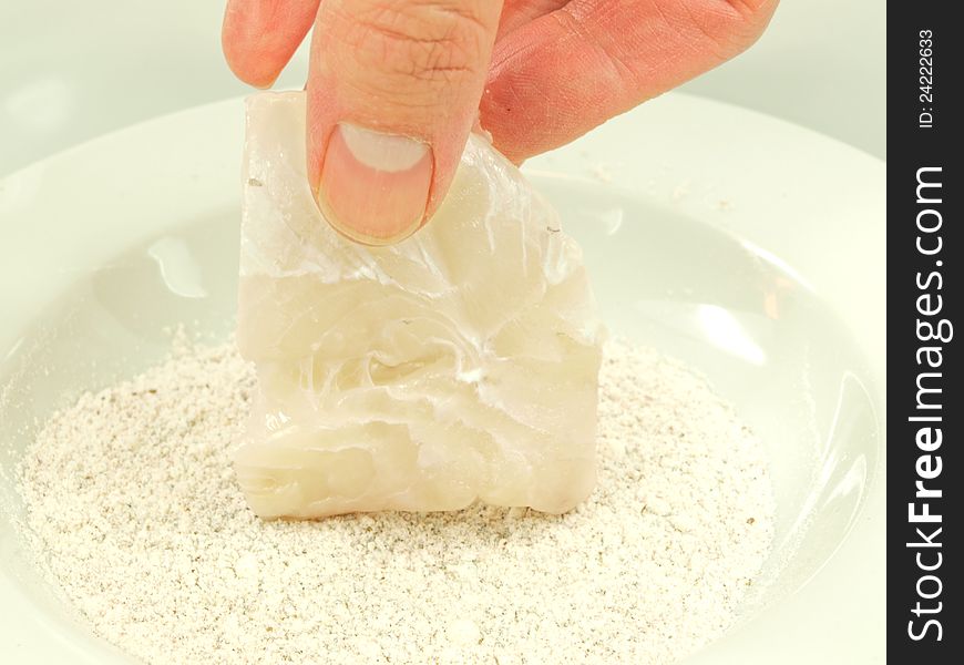 Person adding seasoning to a white fish fillet. Person adding seasoning to a white fish fillet