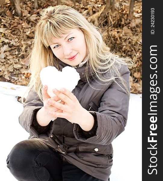 Girl holding heart fashioned out of snow. Girl holding heart fashioned out of snow