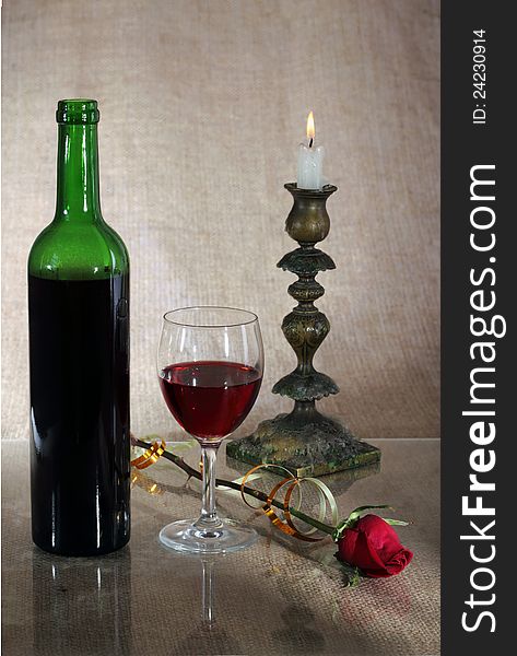 Bottle with red wine and a glass against a sacking