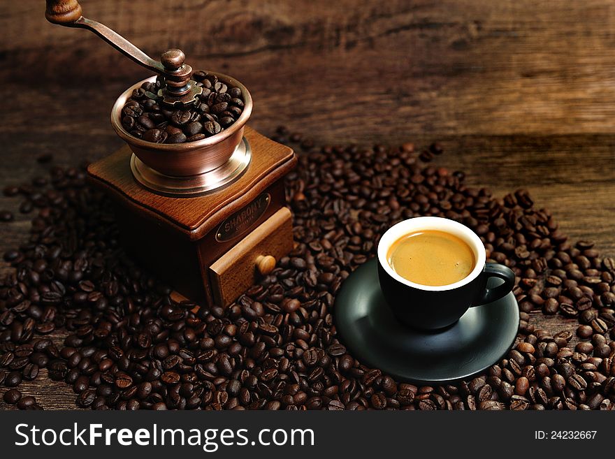 Mage of roasted coffee beans, coffee cup, and ground beans on a wooden table. Mage of roasted coffee beans, coffee cup, and ground beans on a wooden table.