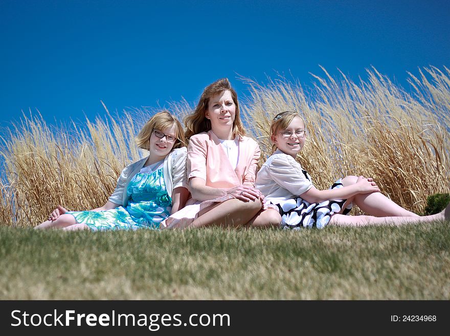 Image of a mother and her 2 daughters sitting in a park. Image of a mother and her 2 daughters sitting in a park