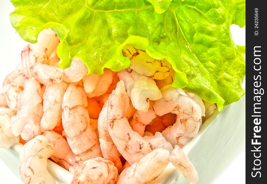 Peeled shrimps, isolated in a white bowl, lettuce on top. Peeled shrimps, isolated in a white bowl, lettuce on top