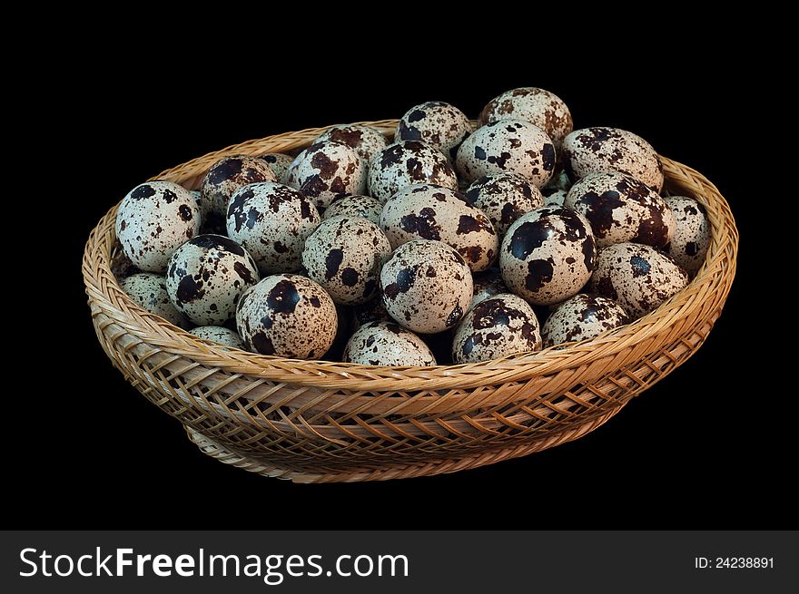 The photo shows quail eggs  close up on black background in basket