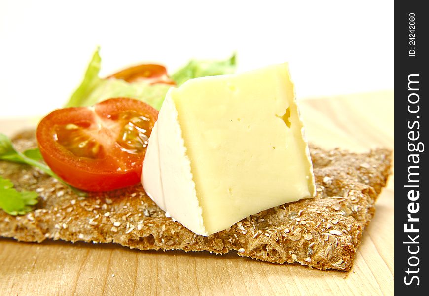 Cracker on wooden board, with soft cheese and tomato. Cracker on wooden board, with soft cheese and tomato