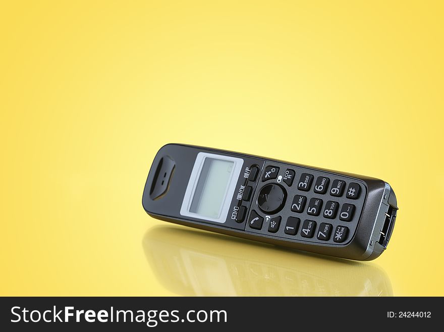 Black telephone receiver with reflection on yellow background