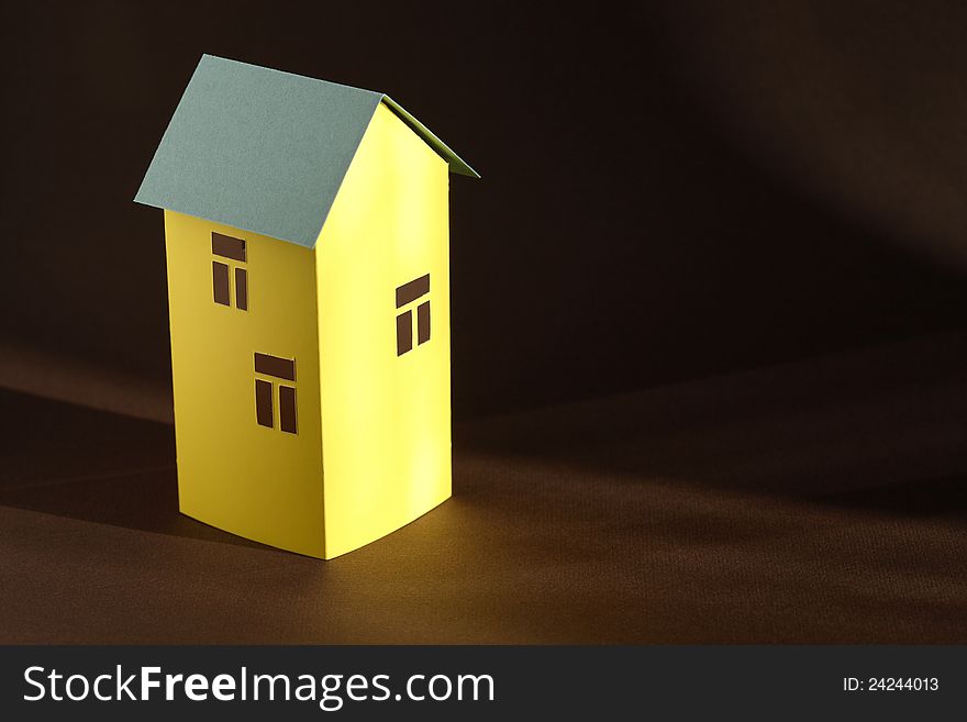 Nice yellow paper house with green roof on dark background