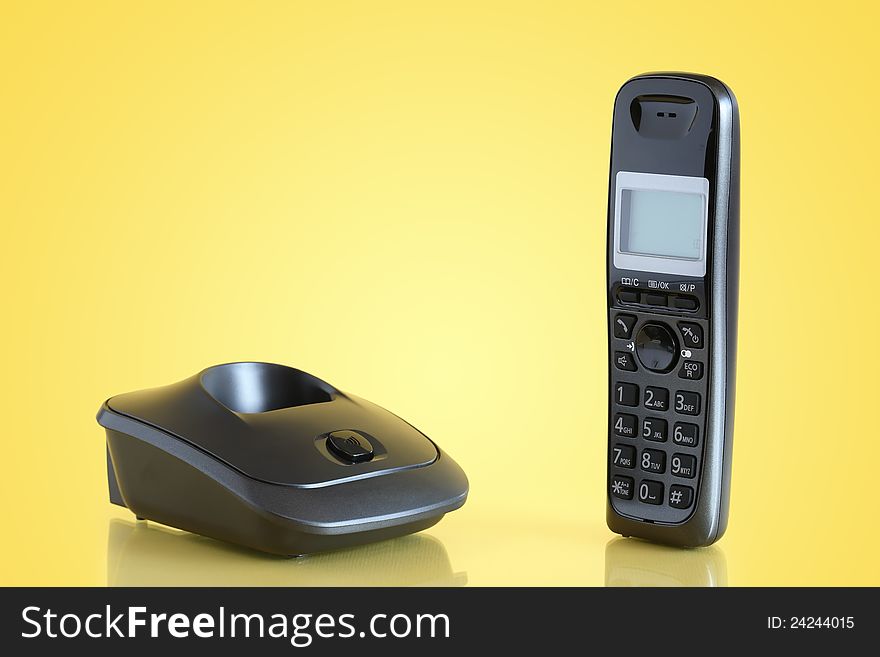 Modern black wireless telephone on yellow background
