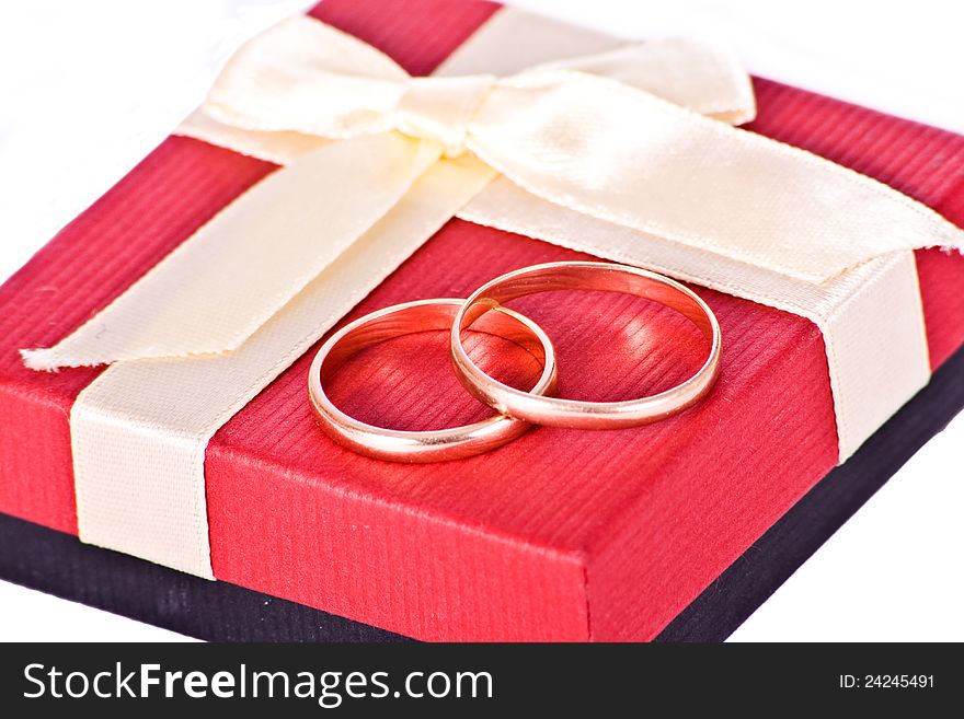 Golden wedding rings near the red gift box Isolated on white background