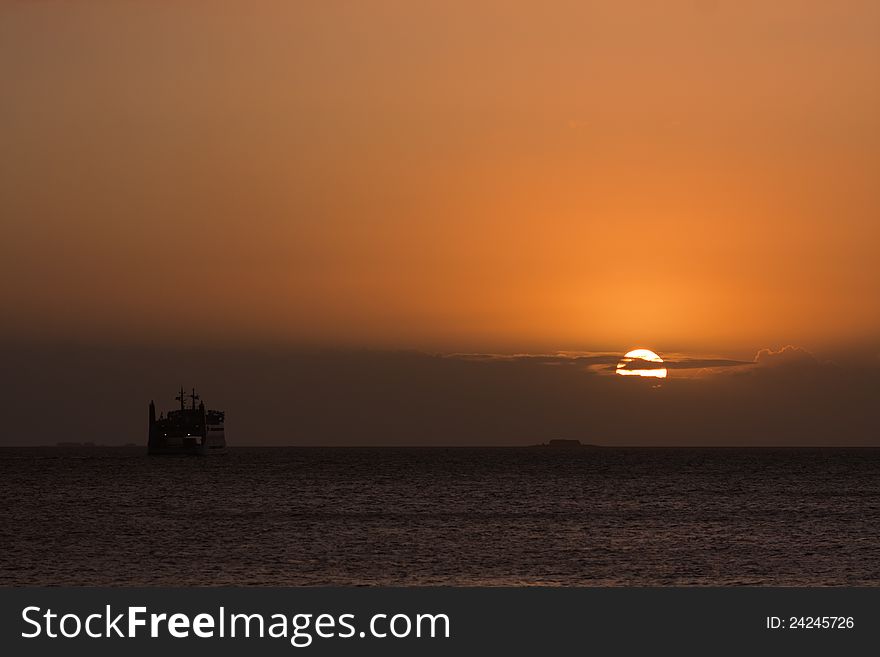 Sunrise over the sea with a ferry